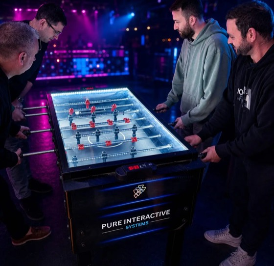 Four players around a Pure Interactive Systems football table in a late-night venue